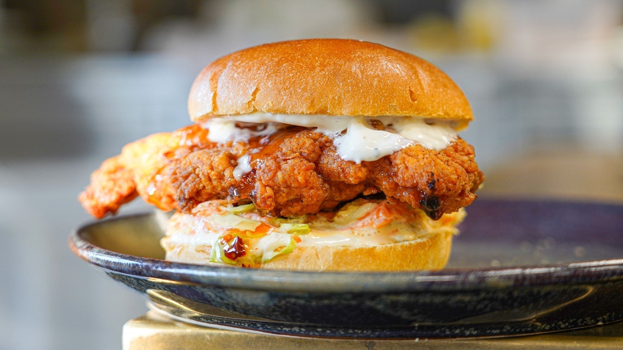 Fried chicken burger met limoenmayonaise, romige coleslaw & hot honey