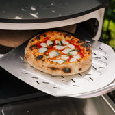 Pizza wordt op een pizzaschep uit de pizzaoven gehaald