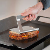 Smasher drukt een sandwich plat op een bakplaat